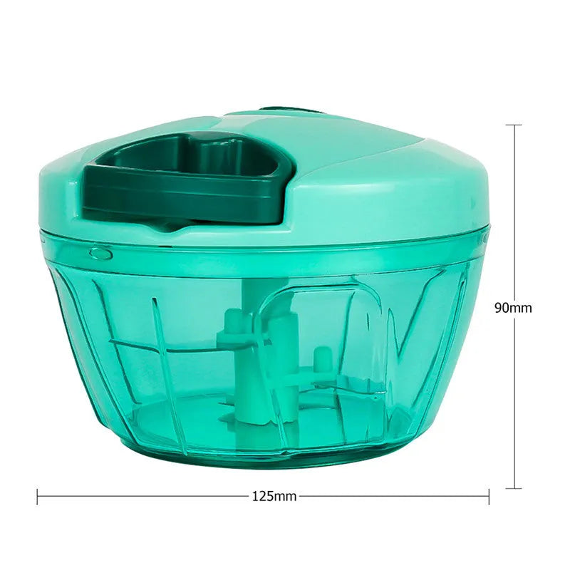 Green manual kitchen chopper with stainless steel blades next to chopped vegetables on a counter.
