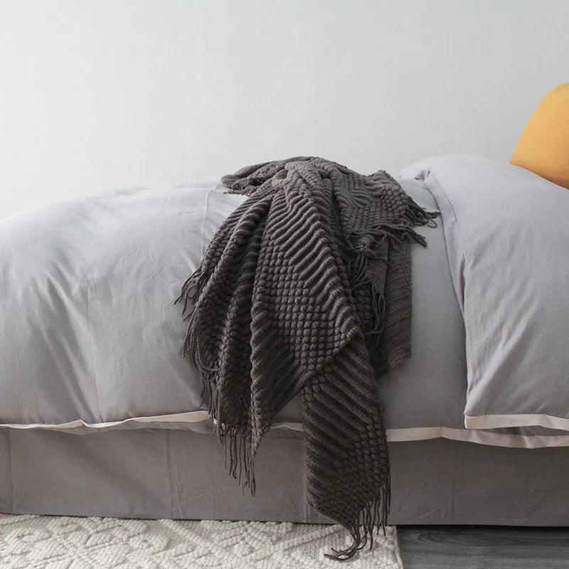 Small light grey polyester throw blanket folded on a sofa, showing its compact 127x170cm size.