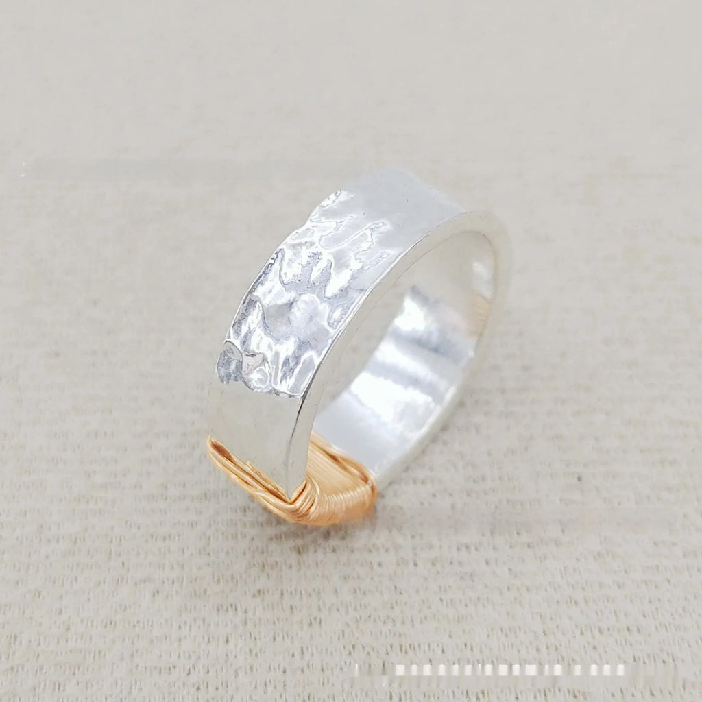 Geometric copper ring bracelet with a wide face and irregular coil design in a silver gold colour.
