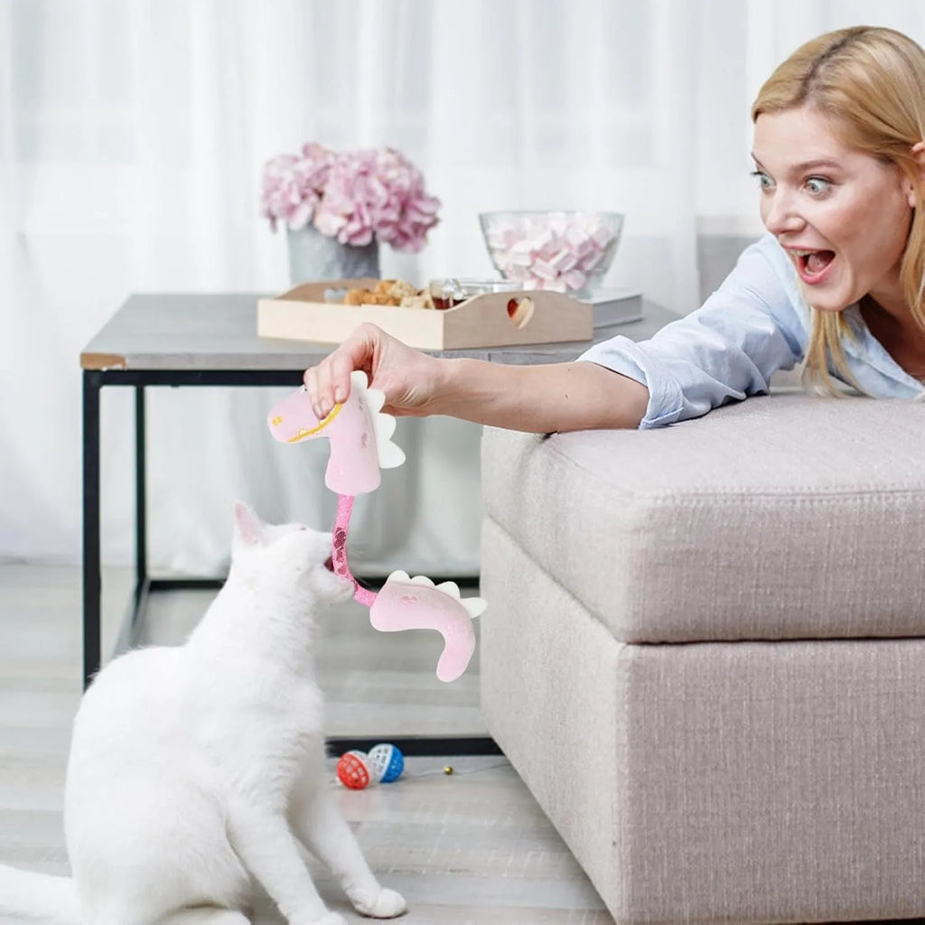 Set of cat toys including plush animals, rope toys, and springs on a pink background
