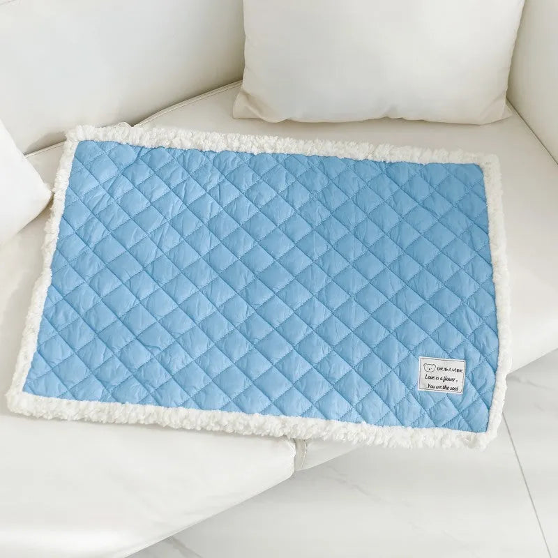 Quilted blue terry cloth pet blanket for cats shown on a pet bed.