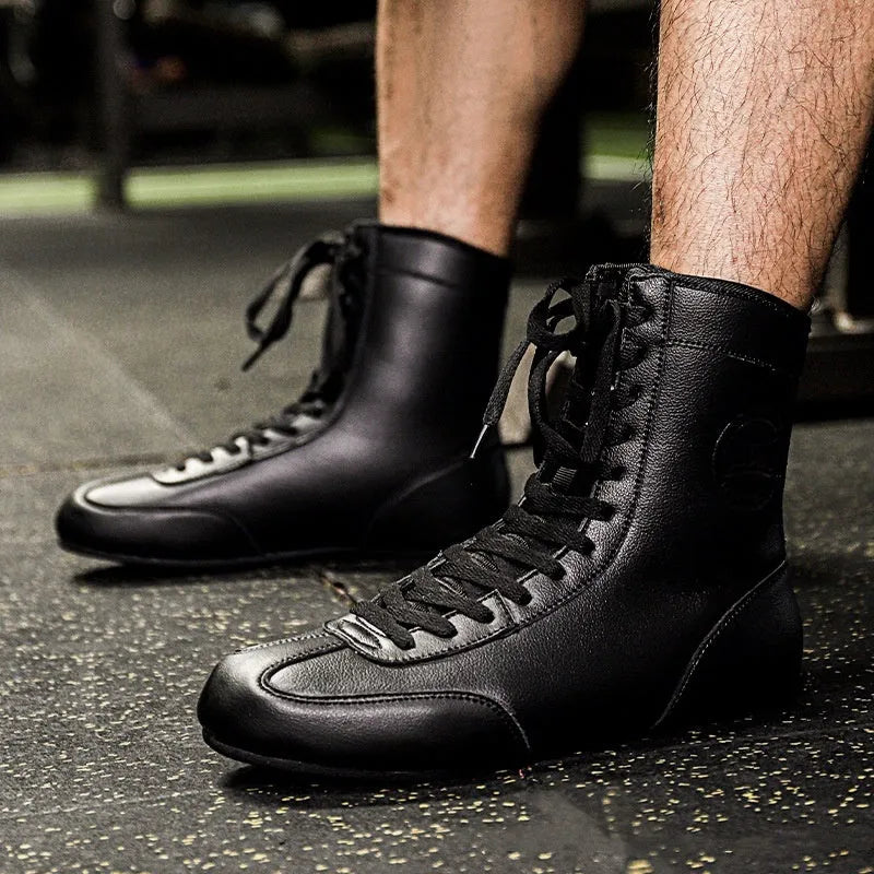 Black and gold mesh professional boxing shoes for men and women on a gym mat.
