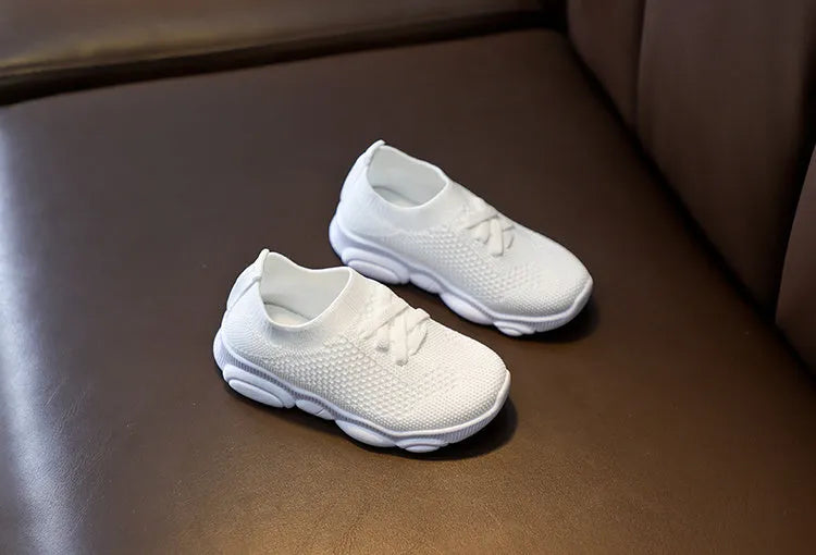 Children's fabric lazy shoe with a non-slip rubber sole, shown in colour options of white, black, pink, and grey.