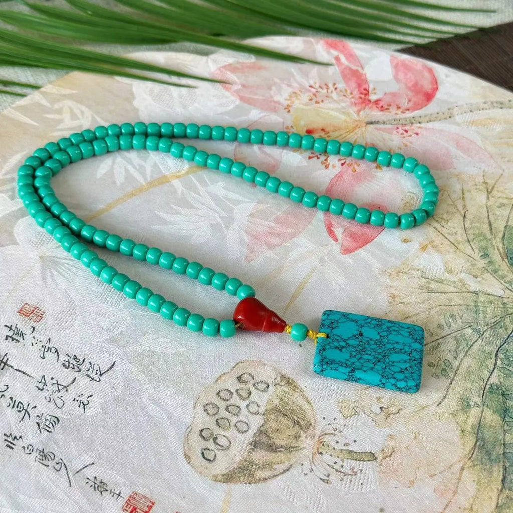 Hand-woven turquoise mesh flower pendant necklace on an adjustable ball bead chain.
