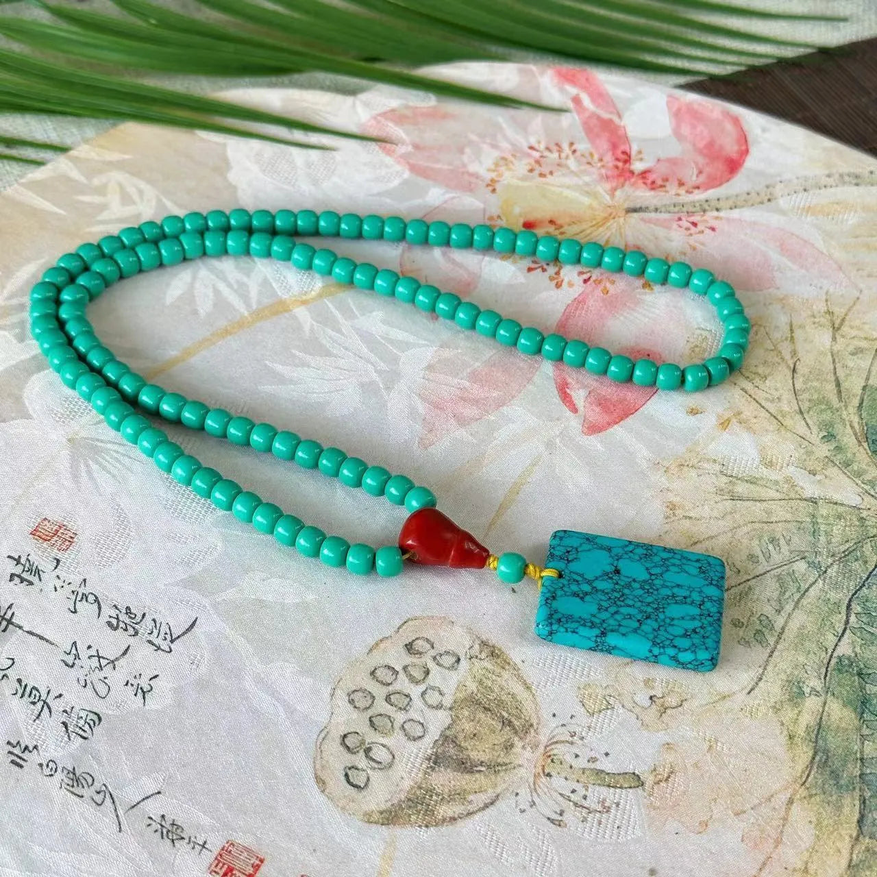 Hand-woven turquoise mesh flower pendant necklace on an adjustable ball bead chain.
