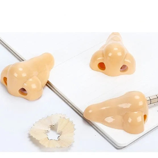 Flesh colour geometric plastic pencil sharpener with large nostril on a white background.