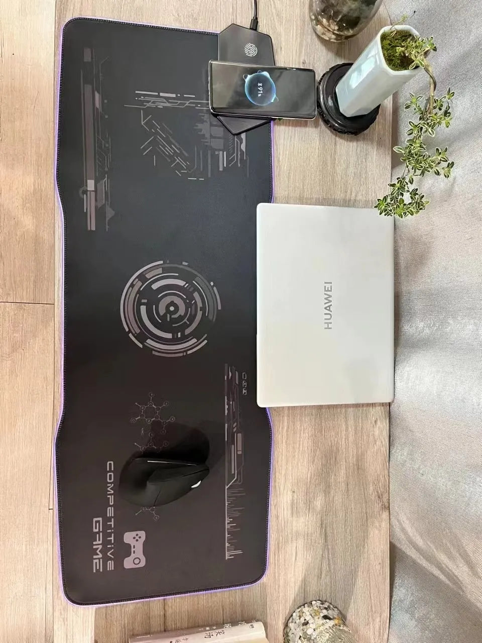 Large black gaming mouse pad with luminous edge lighting on a desk.