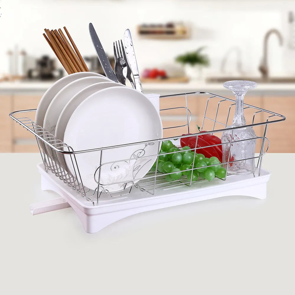 Black stainless steel dish drying rack with plastic cutlery holder and drain board on a kitchen counter.