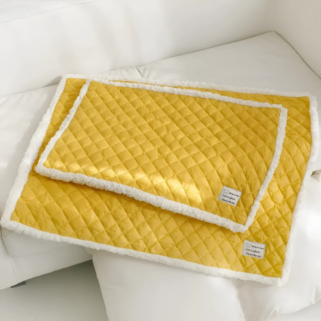 Quilted blue terry cloth pet blanket for cats shown on a pet bed.