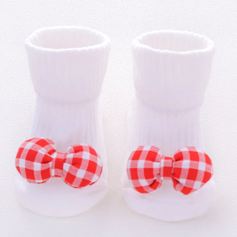 Cotton baby floor socks in a pink bow pattern, shown on an infant's feet.