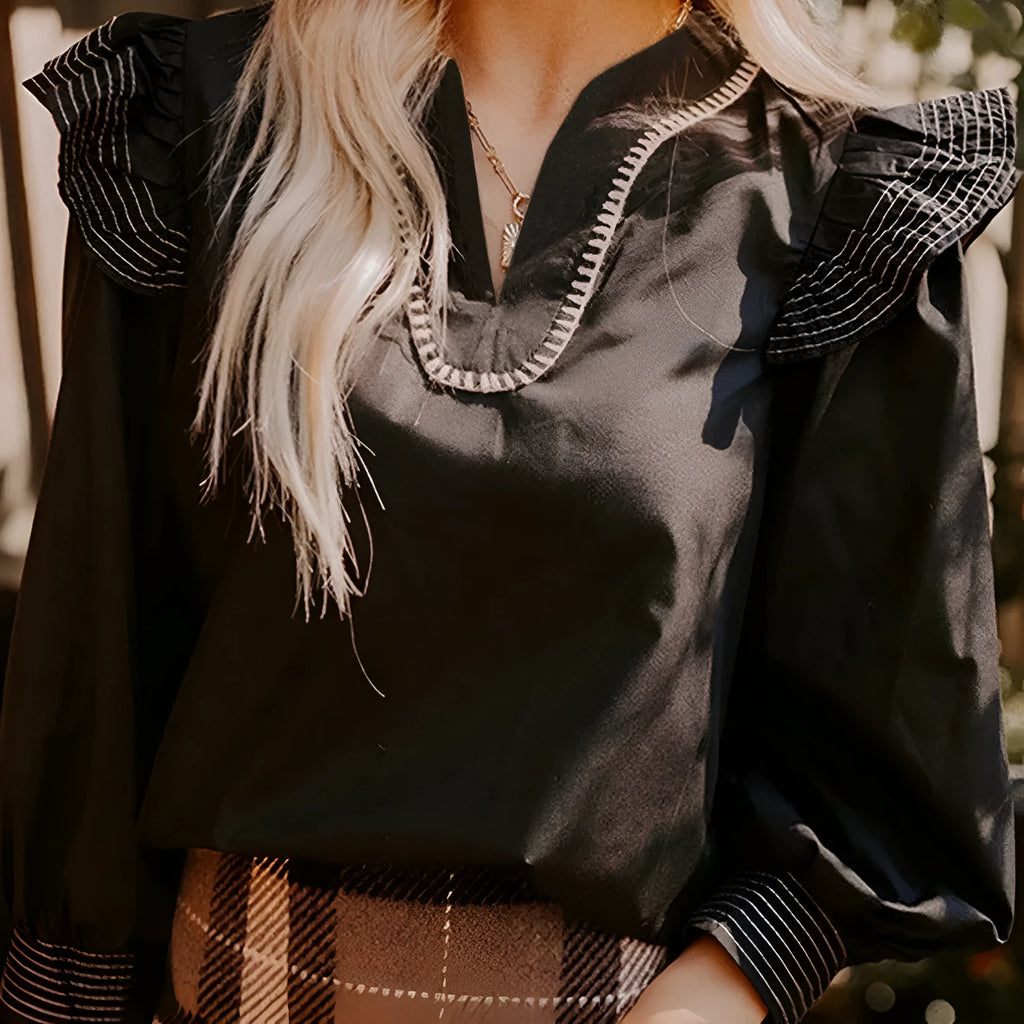 Black women's long sleeve blouse with V-neck, ruffle sleeves, and contrast stitching.