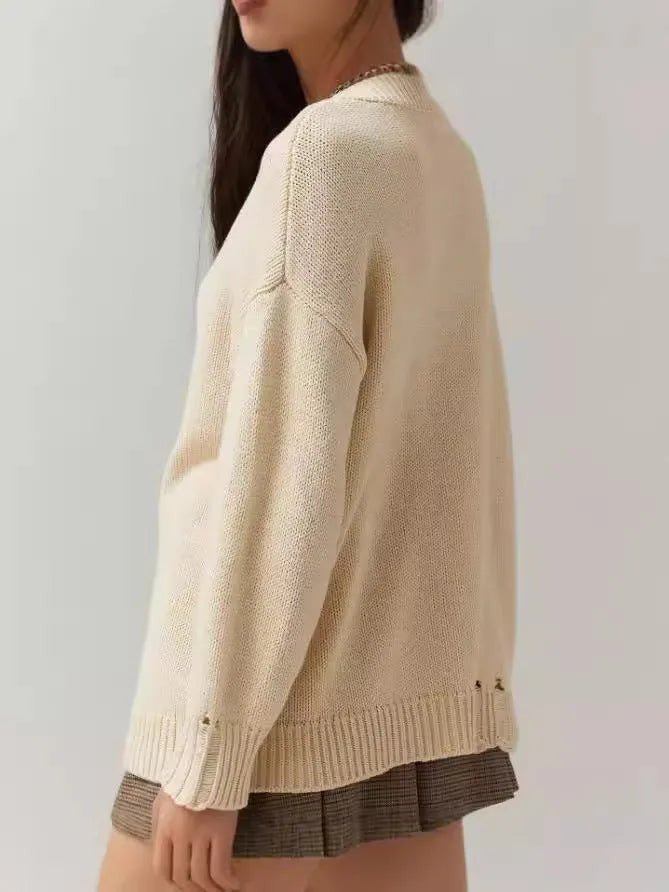 Milky white women's jacquard knit pullover sweater with a round neck and long sleeves on a hanger.