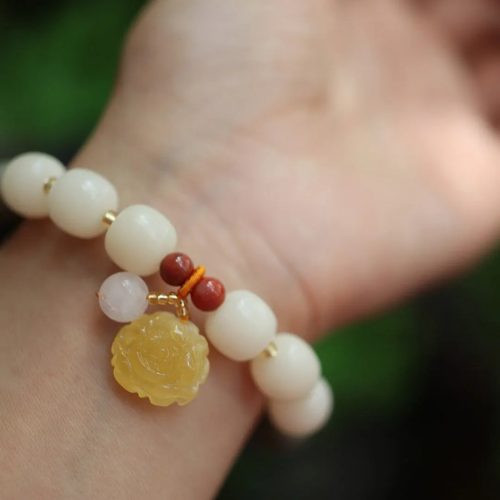 Close-up of a 10mm floral bracelet made from woven Bodhi root with gradient white jade and a natural beeswax lotus bead.