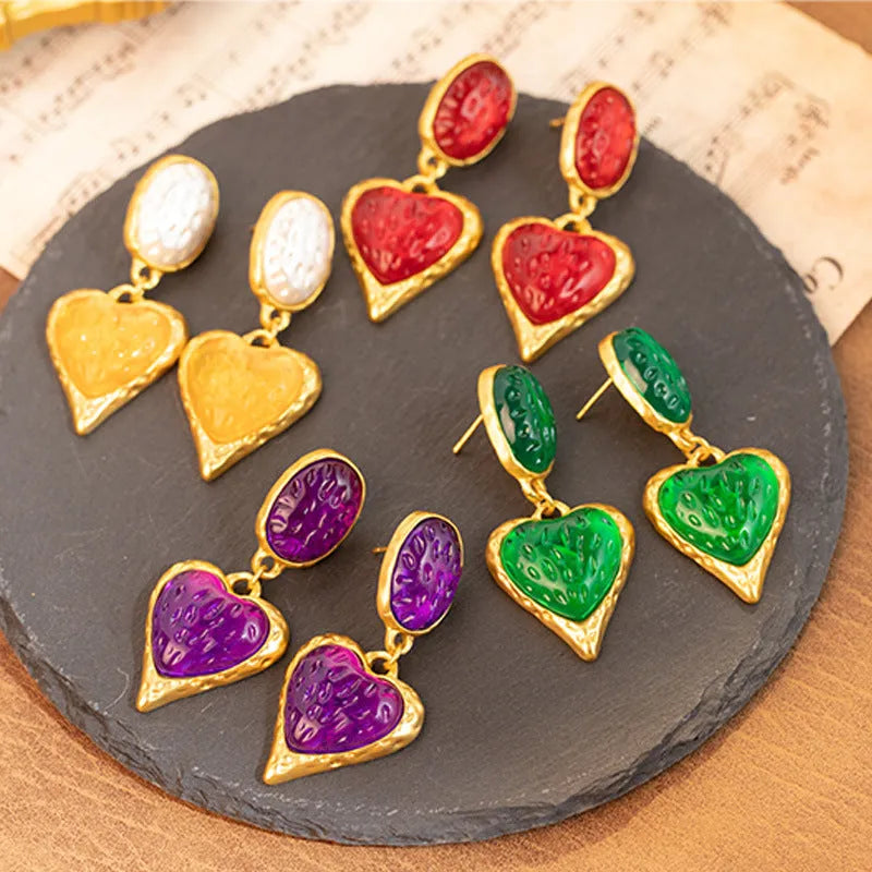 Oval heart-shaped alloy stud earrings with silver pleated edge, shown in purple, red, green, and yellow/white colour options.