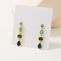 Female green round tassel long geometric earrings on display showing round acrylic and tassel drop