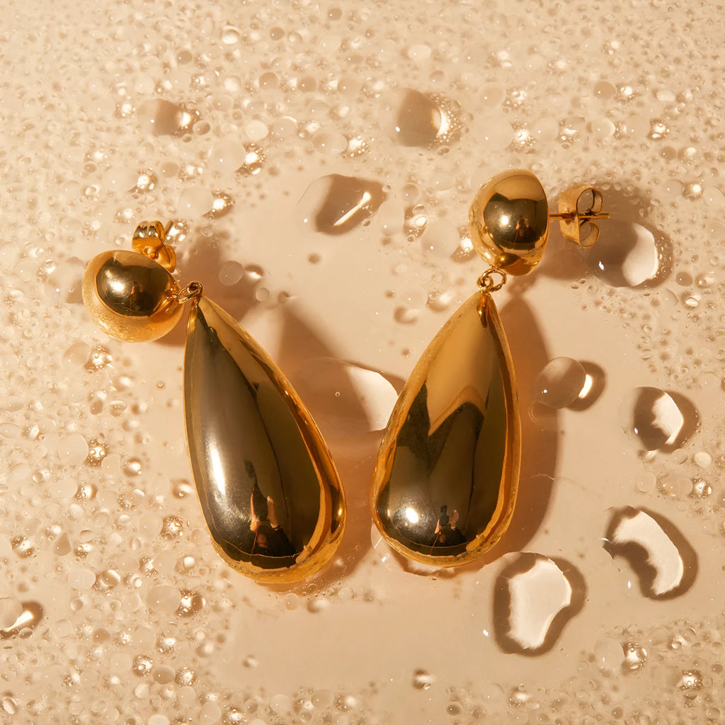 A pair of gold-coloured stainless steel earrings with a geometric water drop pendant design.