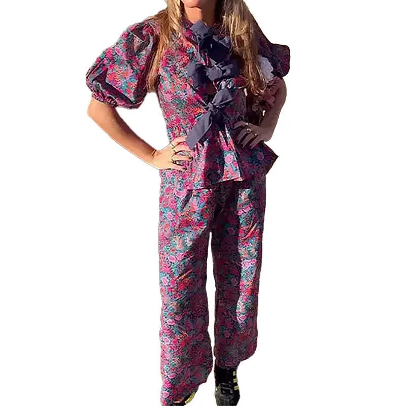 Women's floral print trouser suit set with tie-neck top and puffed sleeves.