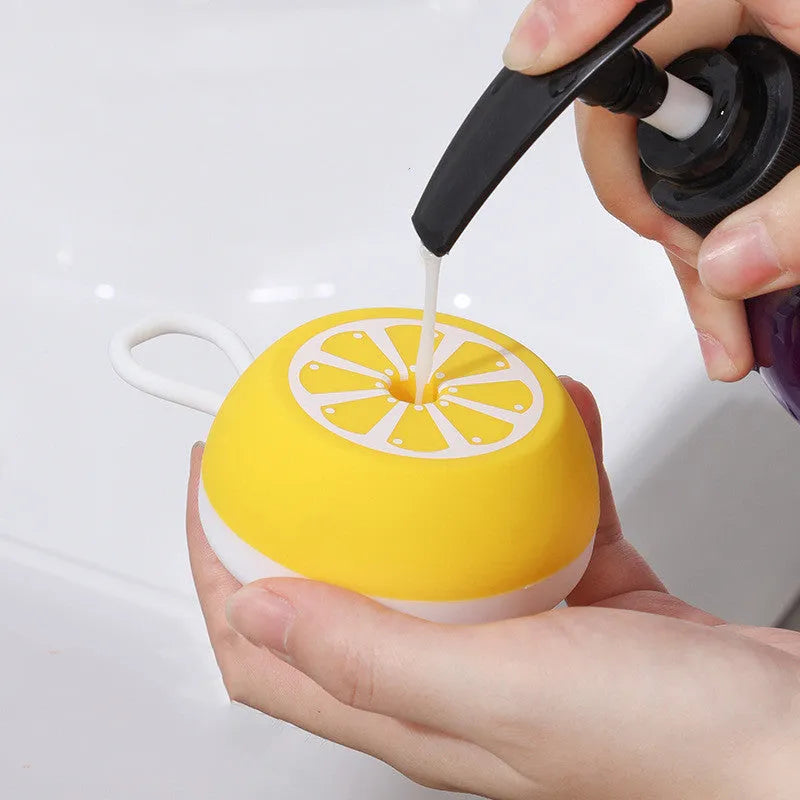 Yellow silicone pet bath brush with massage bristles next to a navy blue comb style brush on a bathroom surface.