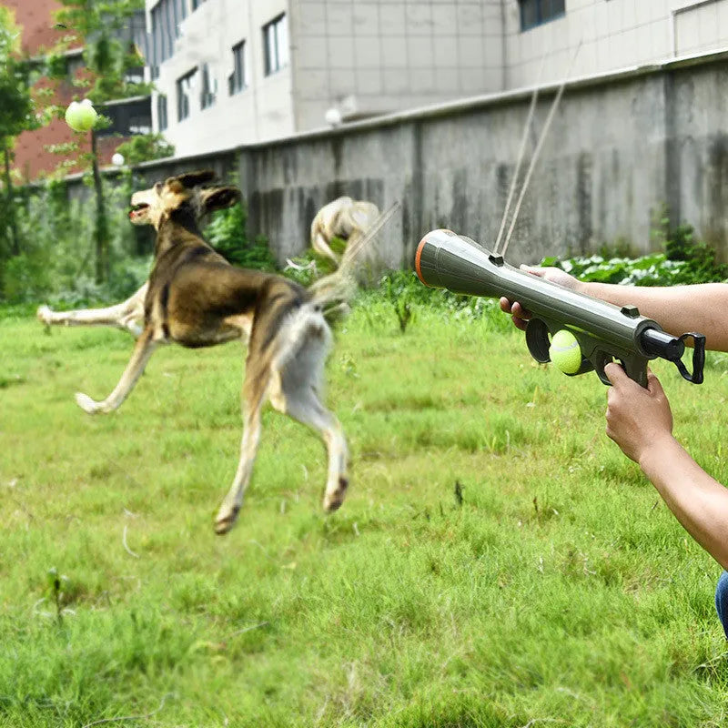 Black ABS plastic tennis ball launcher for dogs with two included tennis balls on grass
