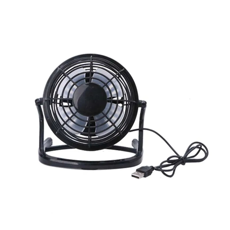 Mini black USB desk fan with adjustable tilt angle on a wooden desk next to a laptop.