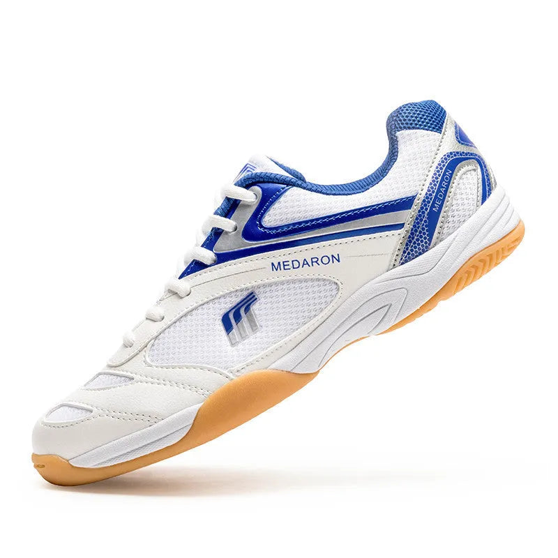 White and blue table tennis shoes with mesh panels and rubber sole on a court surface.