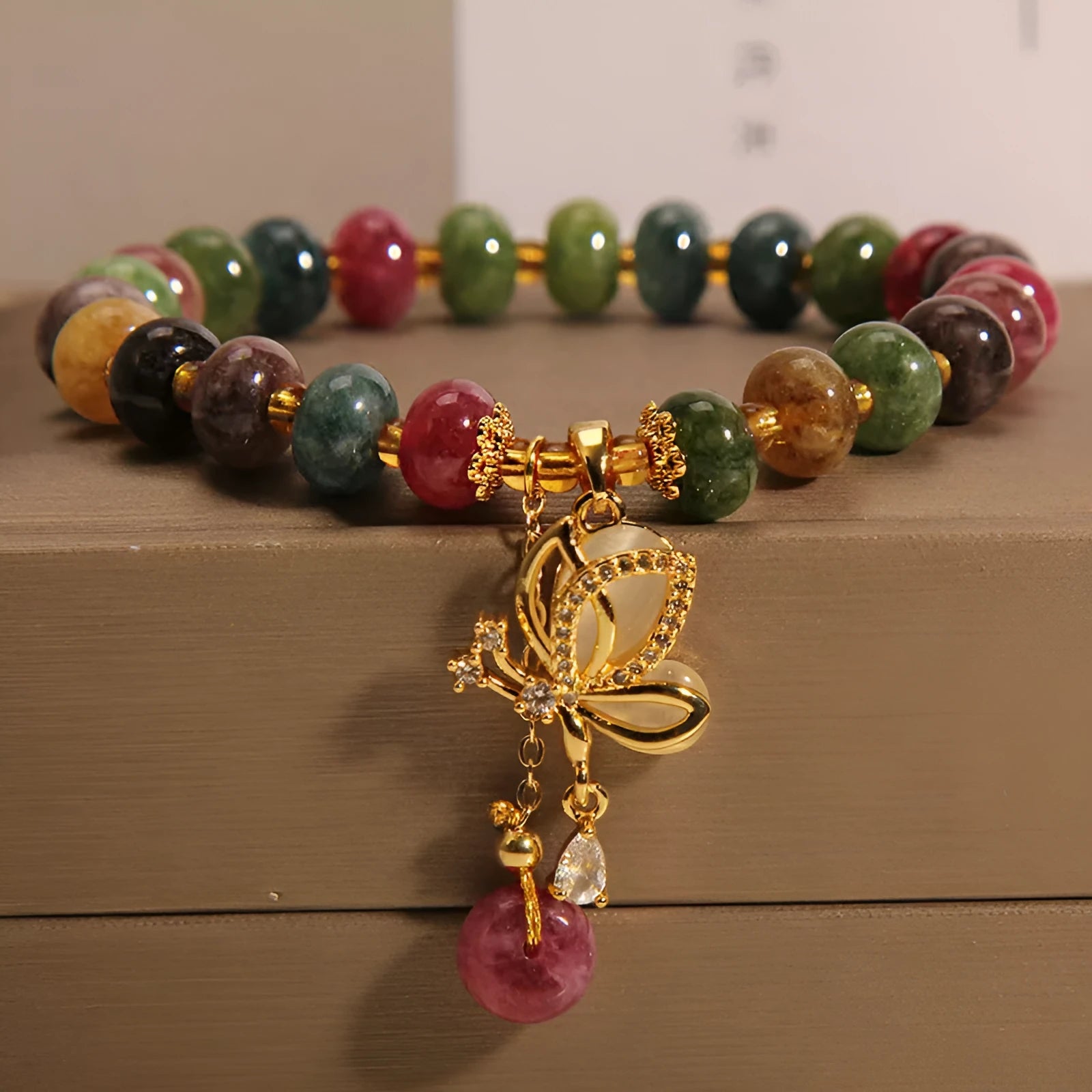 Colourful butterfly bracelet with alloy base and glass beads in tourmaline shades.