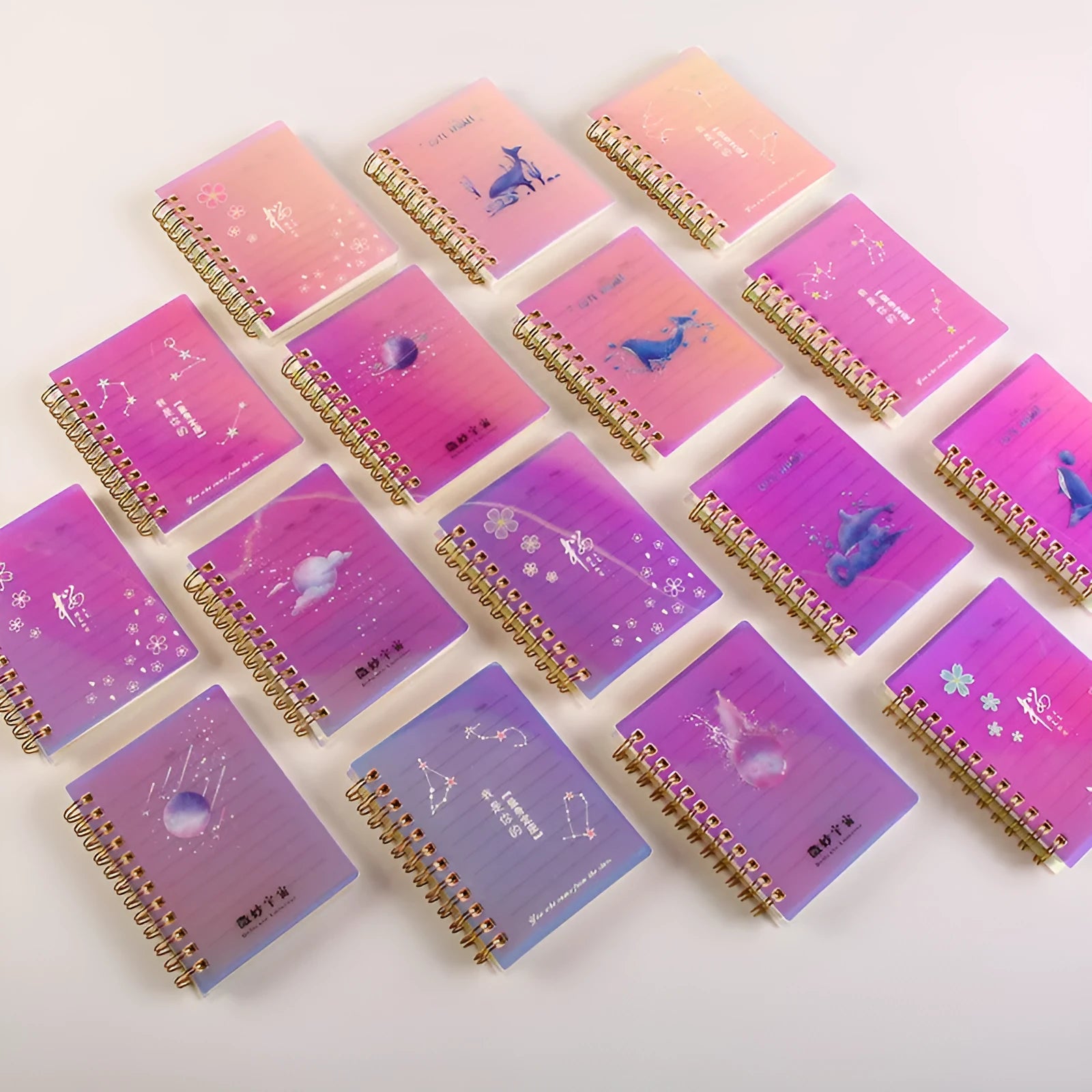 Set of four A7 spiral-bound pocket notebooks with rollover coils, showing Constellation, Sakura, Ocean, and Universe cover designs.
