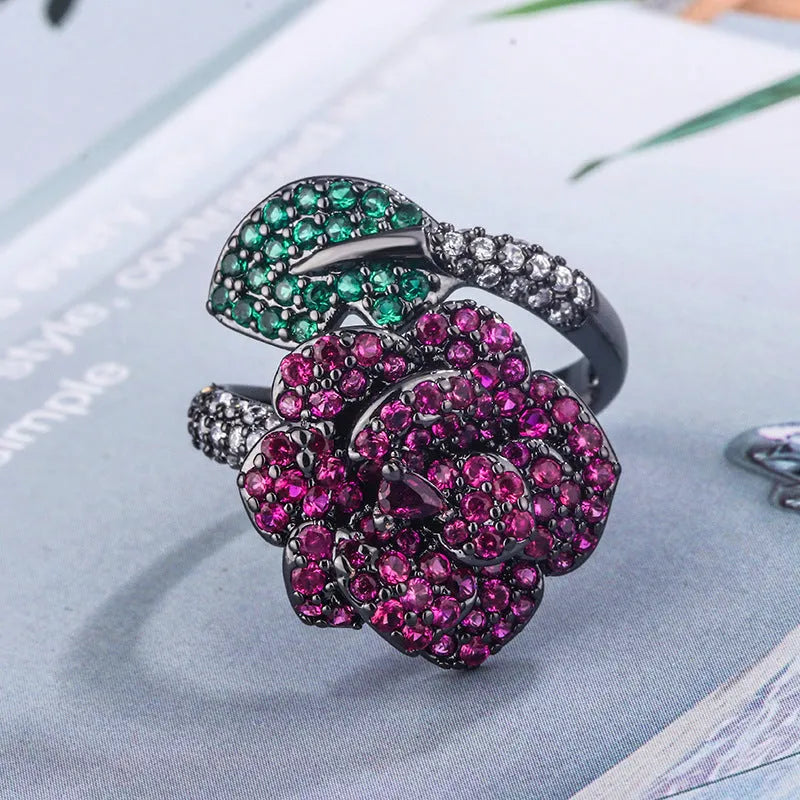 Geometric black gold plated ring with red simulated corundum stone in a floral setting.