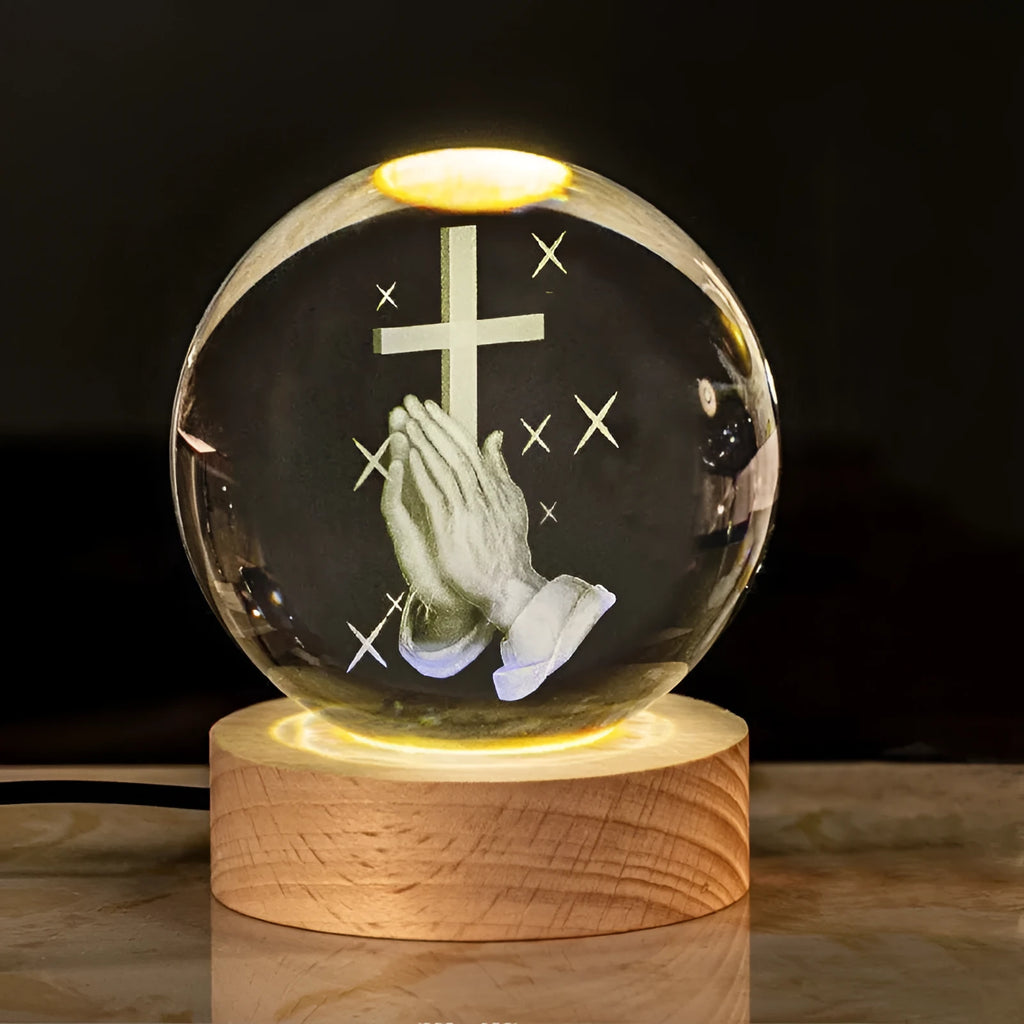 White crystal ball ornament on a wooden base with warm light, showing a detailed Cross design inside.