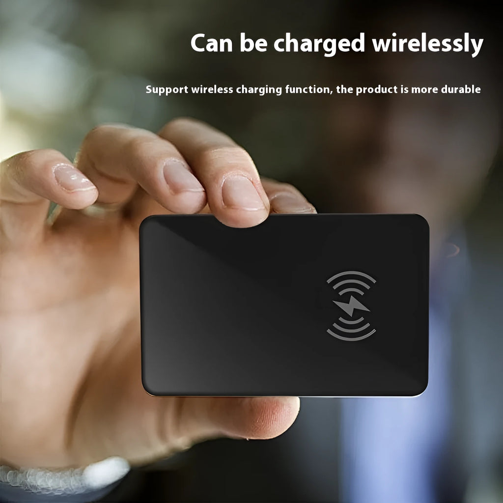 Black credit card-sized pet tracker with wireless charging and a hanging hole, shown next to a coin for scale.