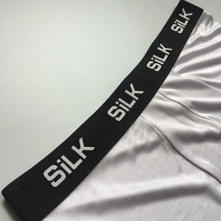 Men's loose-fit silk shorts in navy blue, shown on a mid-waist.