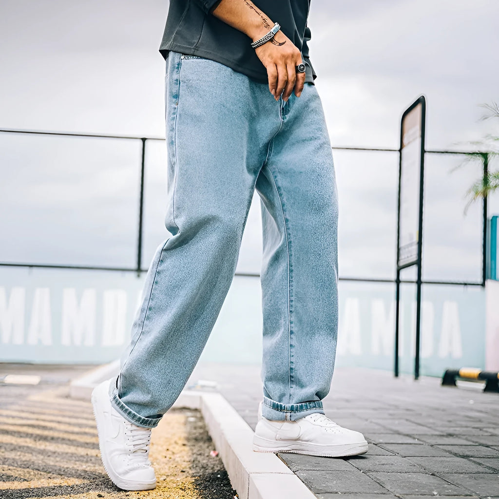 Men's loose straight blue jeans on hanger showing relaxed leg cut and zipper fly