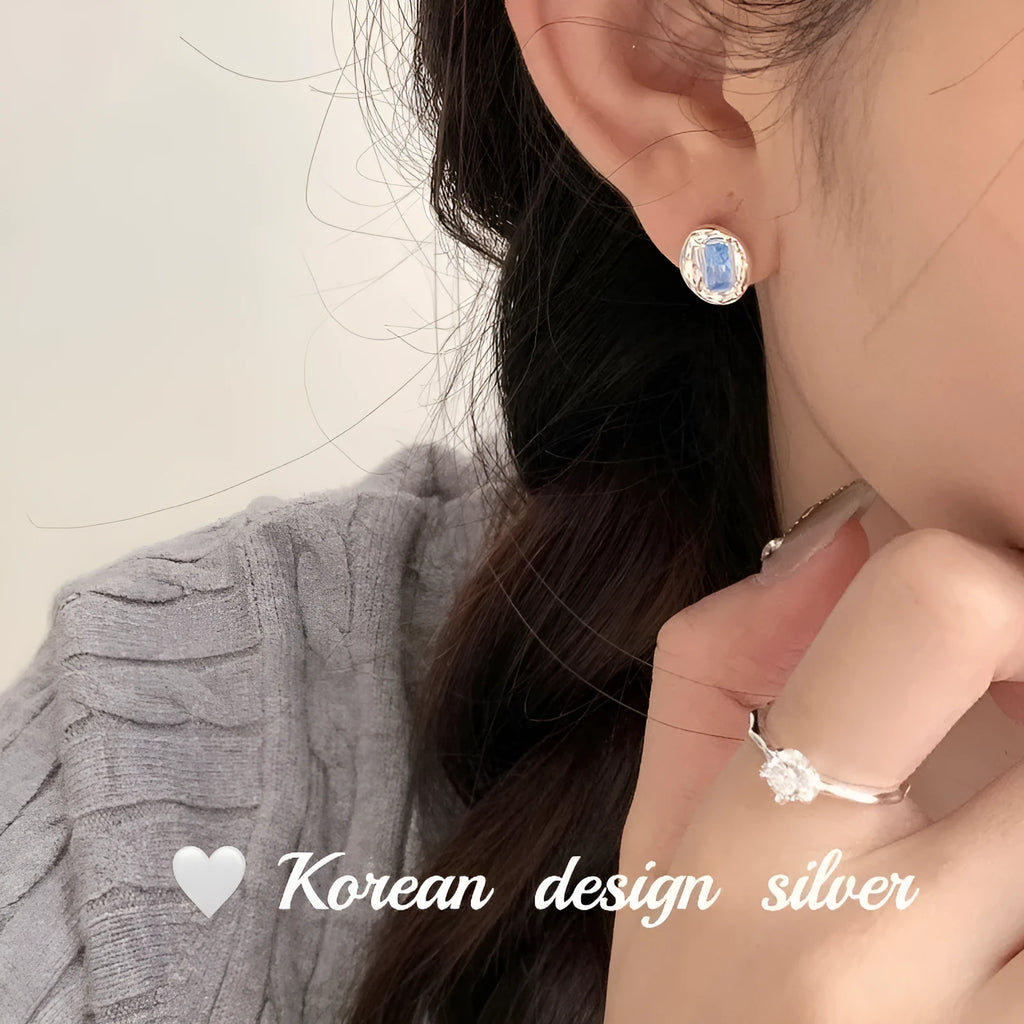 Women's sterling silver earrings with heart-wrapped oval blue diamond centrepiece on silver geometric design