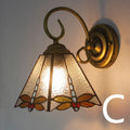 A coloured stained glass wall lamp mounted on a corridor wall, showing one of six available style designs.
