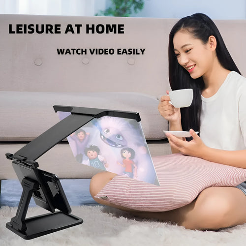 Black folding mobile phone screen magnifier with detachable holder on a desk.