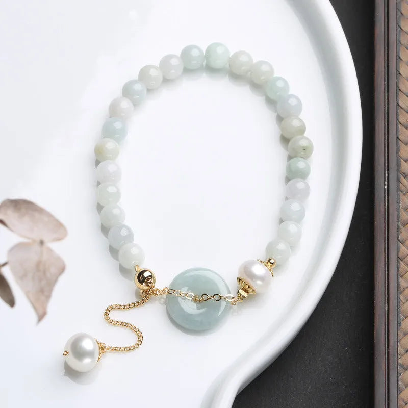 Natural jade bracelet with geometric shape, round pendant, and peace buckle closure on a wrist.