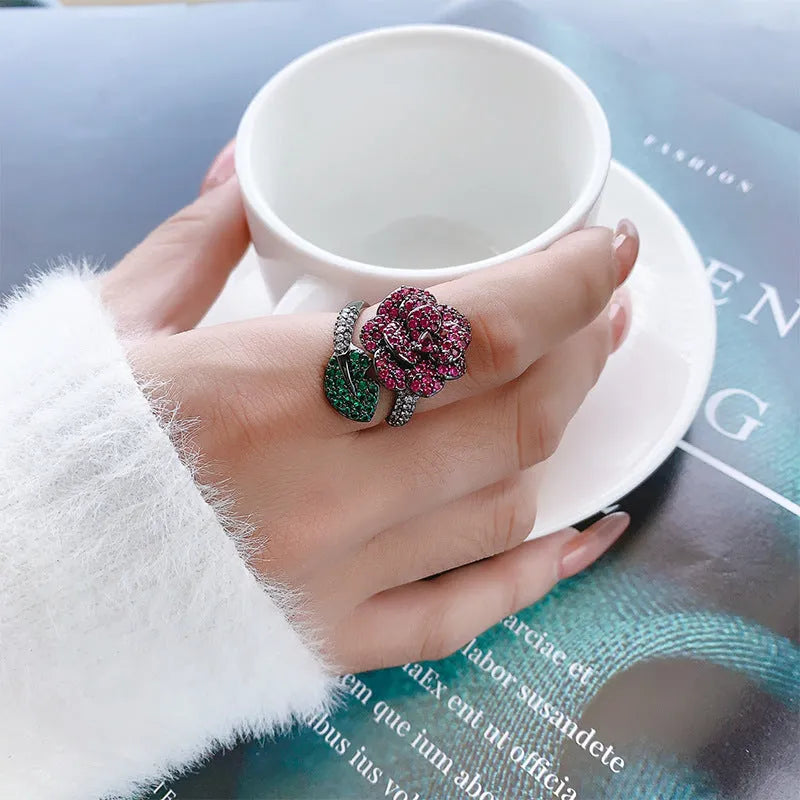 Geometric black gold plated ring with red simulated corundum stone in a floral setting.