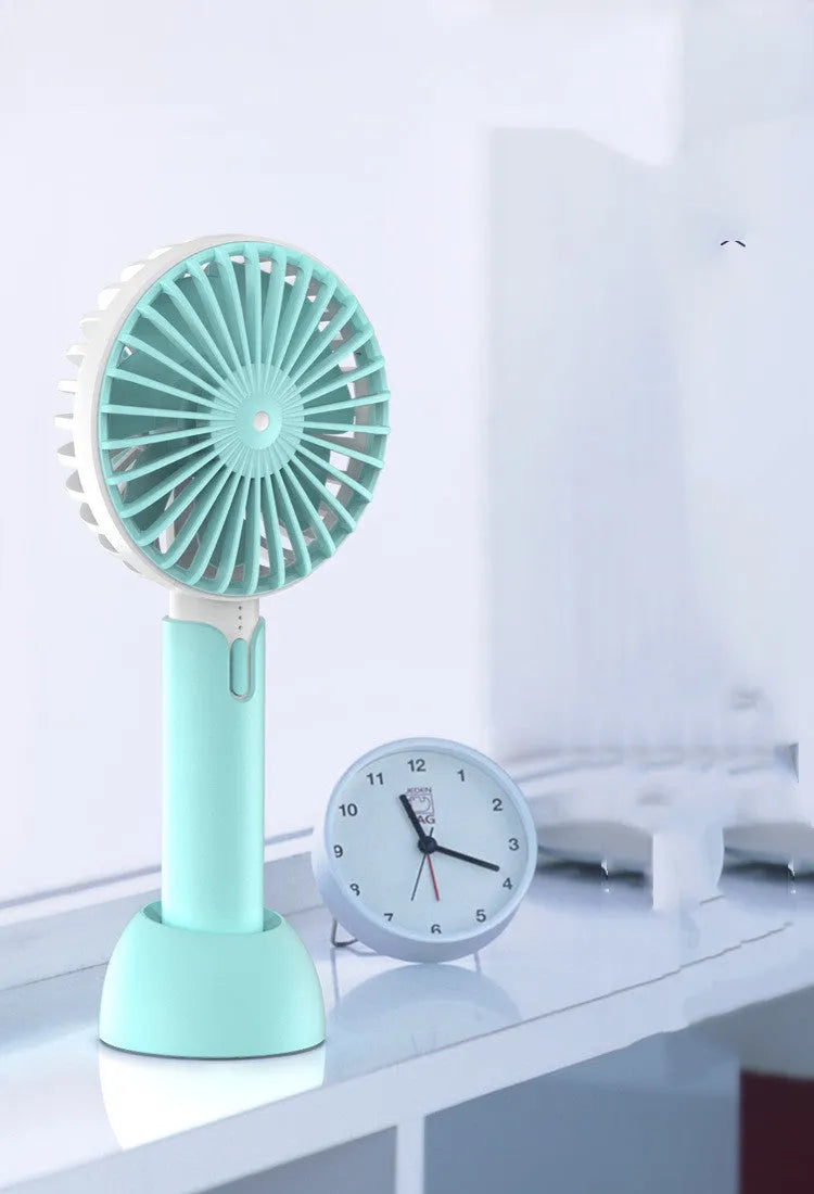 Blue handheld mini USB fan with 3-speed buttons on a desktop.