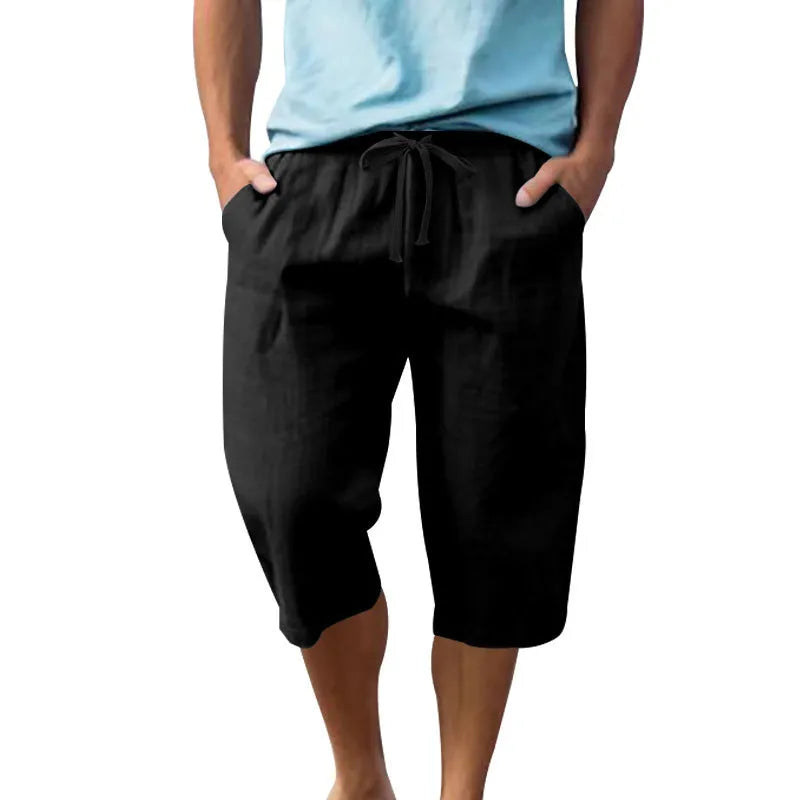 Men's light khaki linen shorts with a drawstring waistband and loose, cropped leg fit.