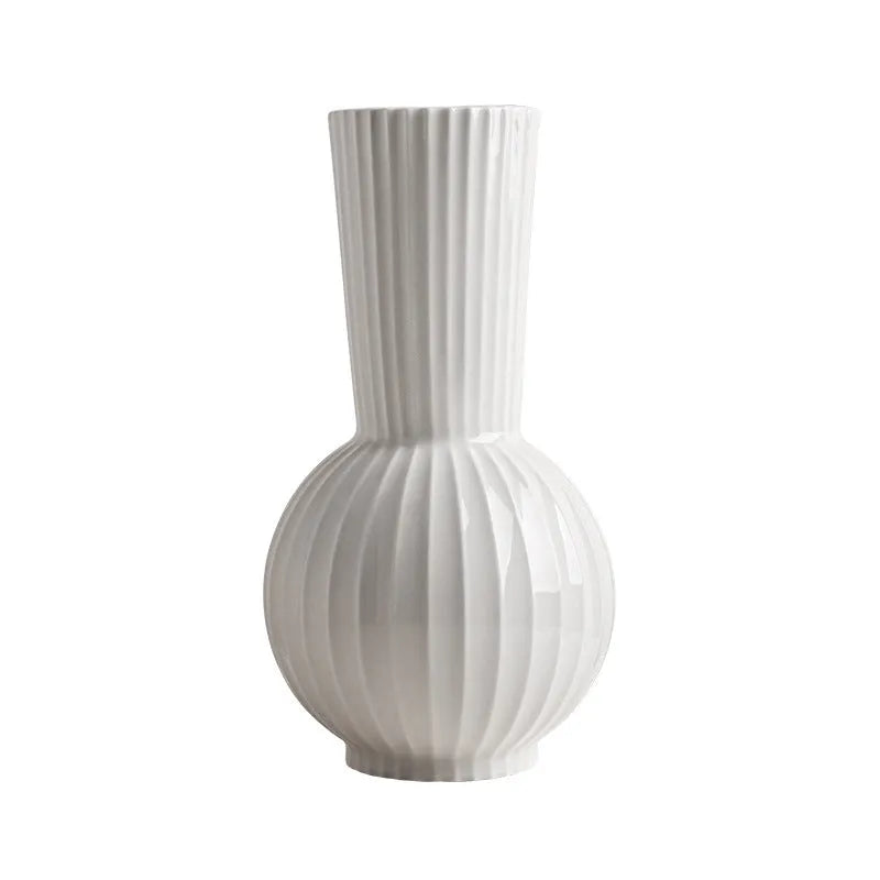 White ceramic ball vase with blue stripes and artificial blue orchid stems on a wooden table.