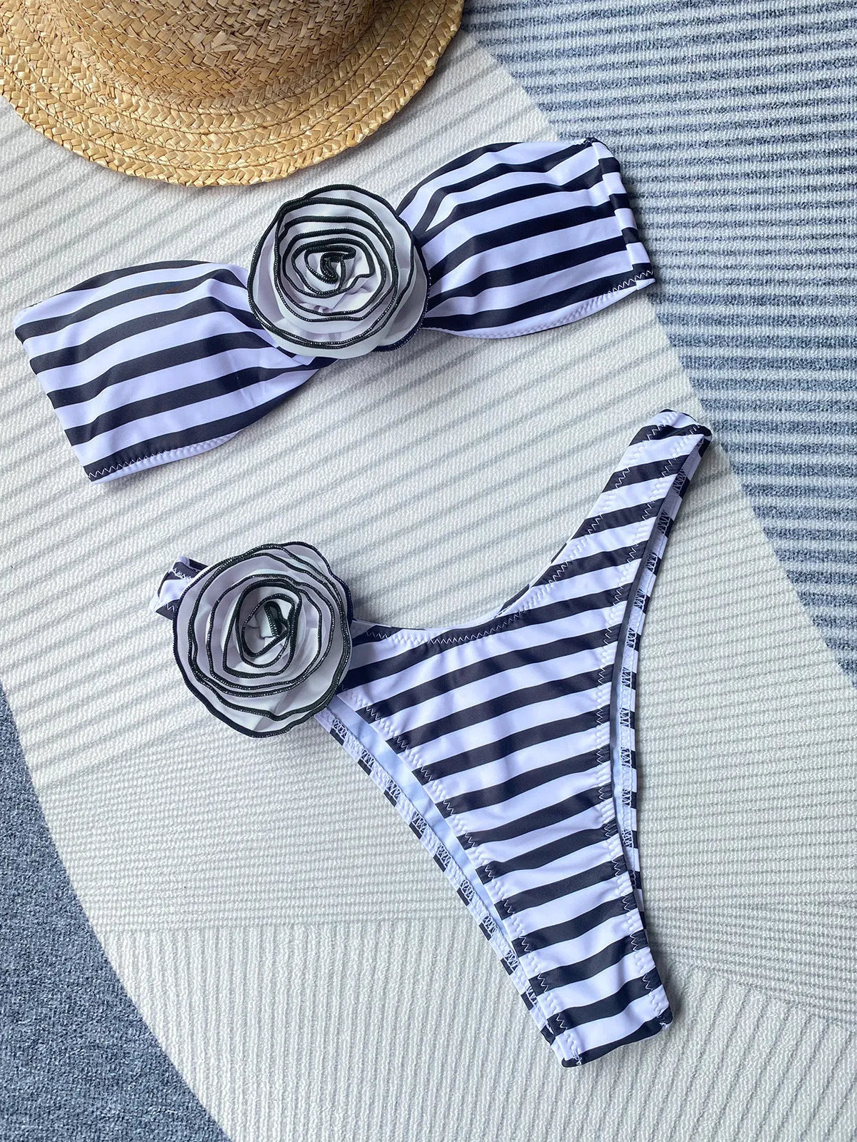 Black and white striped bikini swimsuit with cross-back tube top and floral split shorts on a mannequin.