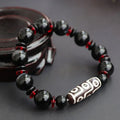 Black agate dzi bead bracelet with hand-woven geometry beads on a wrist.