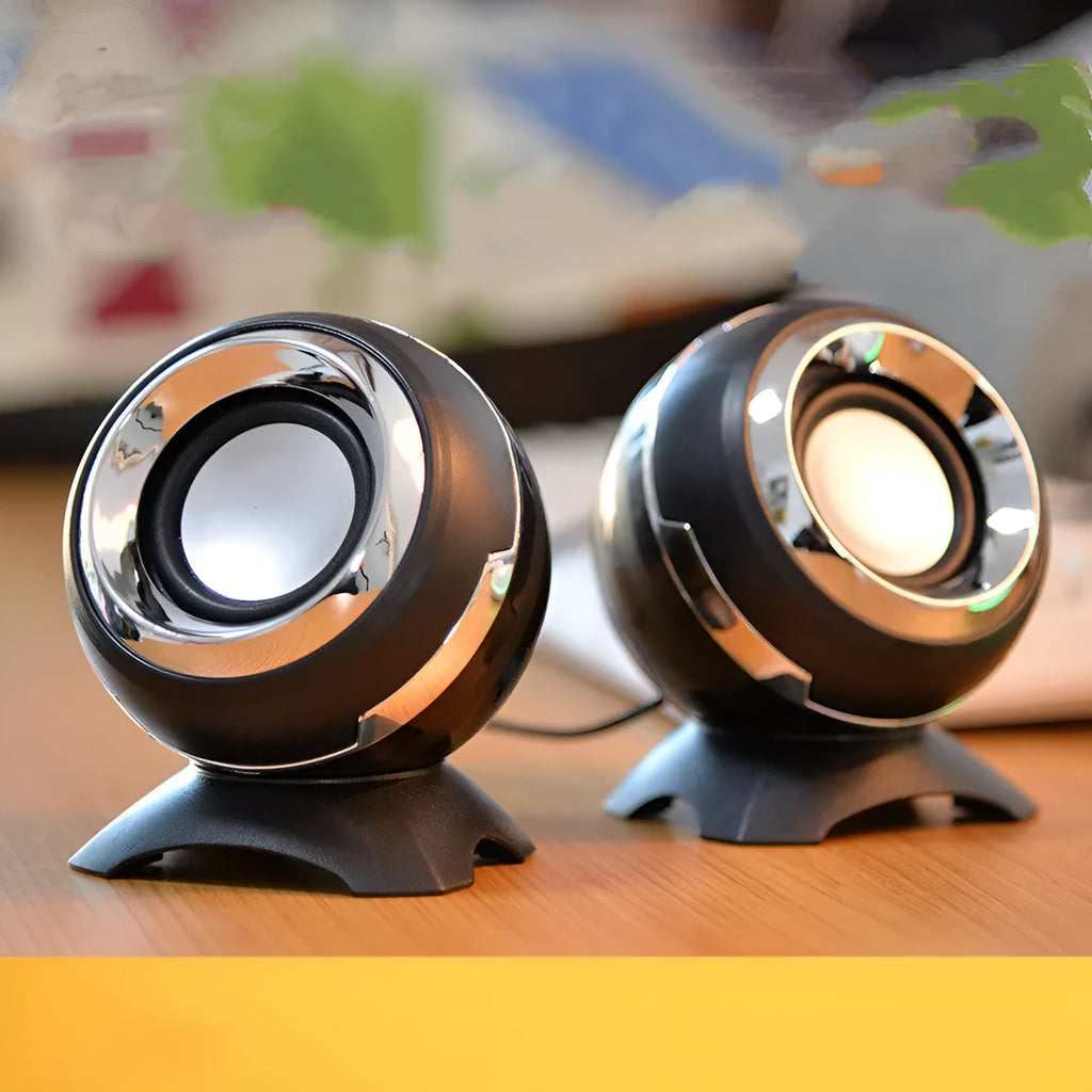 Pair of compact USB-powered desktop speakers in black and gold finish beside laptop computer