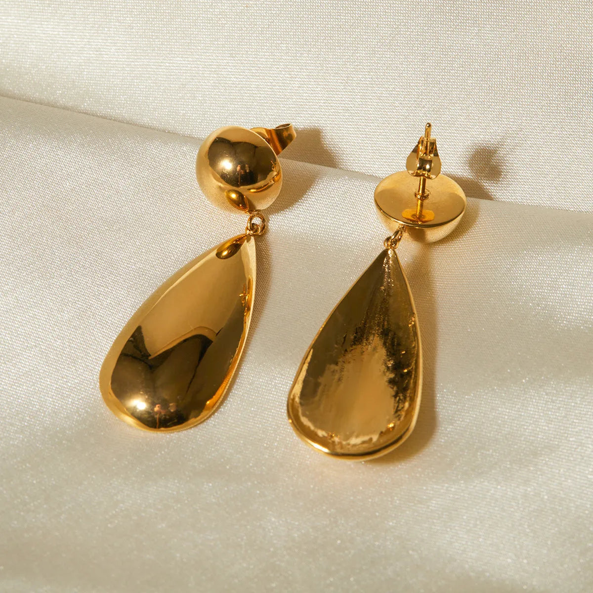 A pair of gold-coloured stainless steel earrings with a geometric water drop pendant design.
