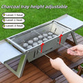 Small foldable metal charcoal grill with a carrying handle, shown in a compact stored position.