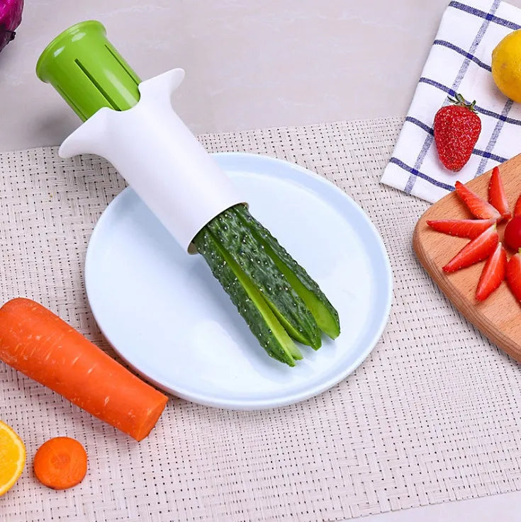 White plastic vegetable and fruit slicer with multiple stainless steel blades for cutting cucumbers, carrots, and strawberries.