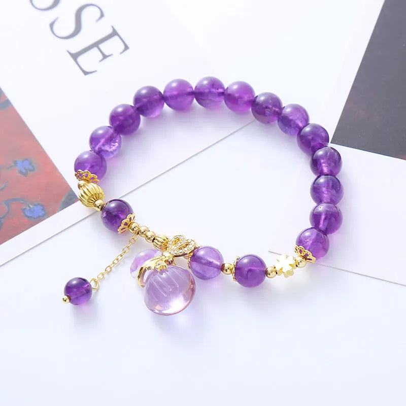 Purple crystal bracelet with ethnic money bag pendant and peace buckle closure on wrist