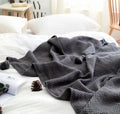 Nordic style knitted acrylic blanket with fringed edges in neutral colour on sofa