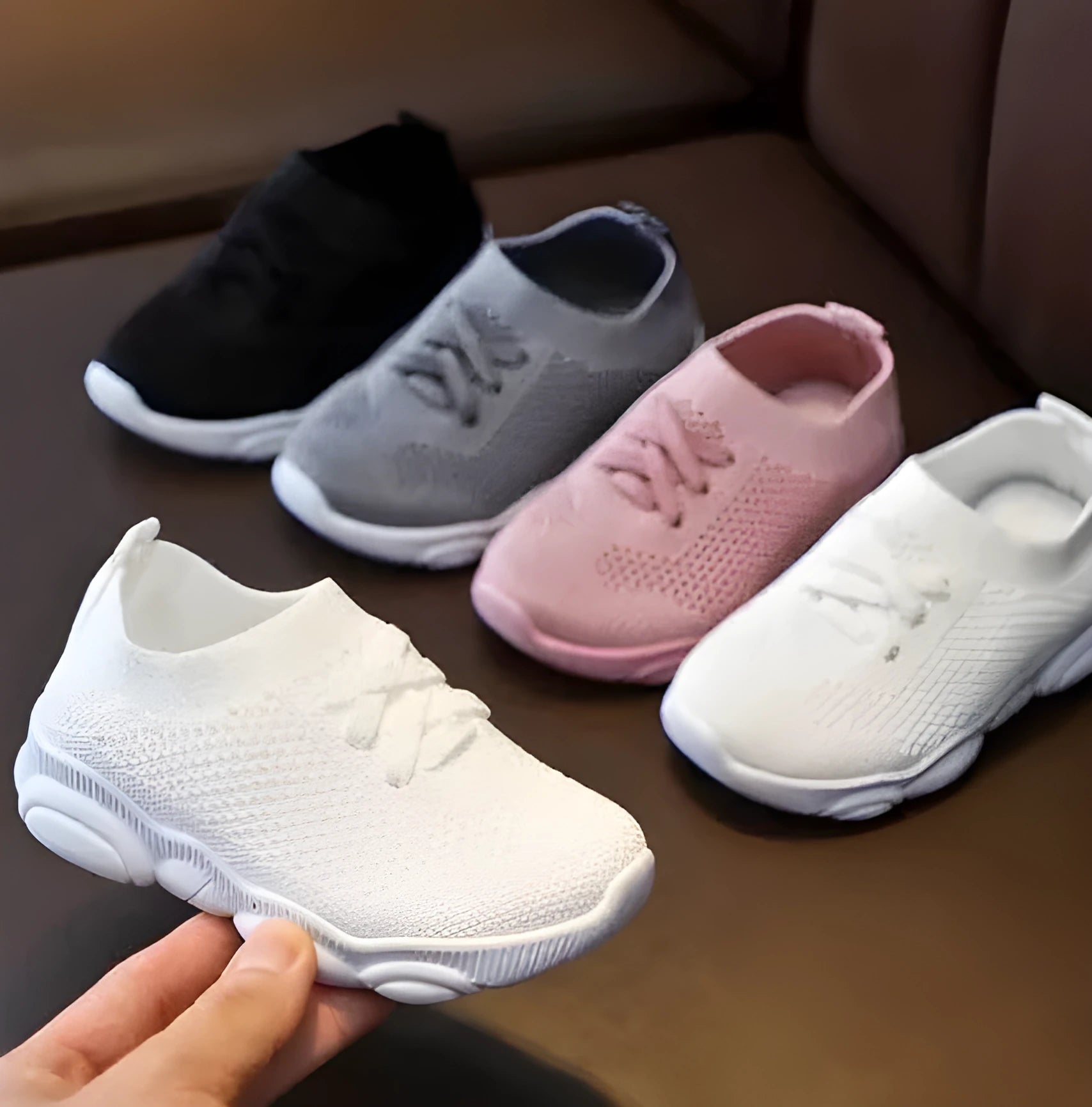 Children's fabric lazy shoe with a non-slip rubber sole, shown in colour options of white, black, pink, and grey.
