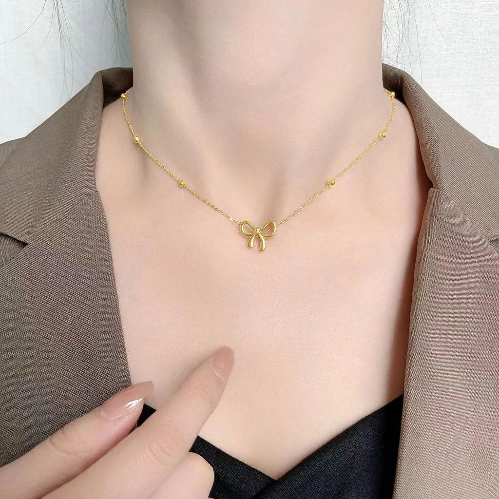 Gold bow necklace on a cross chain, adjustable from 41cm to 50cm length.